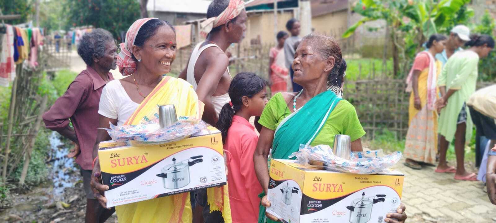 Volunteers carrying relief boxes of pressure cookers