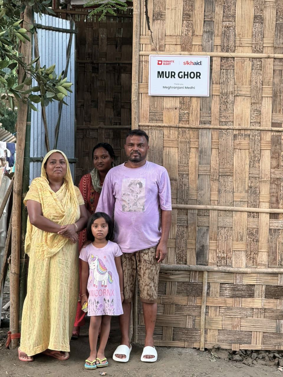 A family stands in front of their new Mur Ghor home