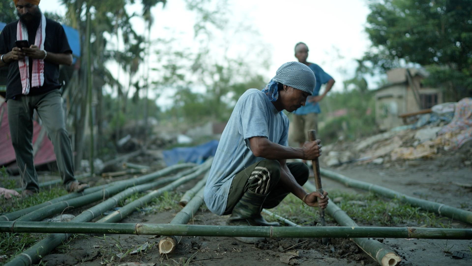 A villager splitting bamboo poles to rebuild after the Assam floods